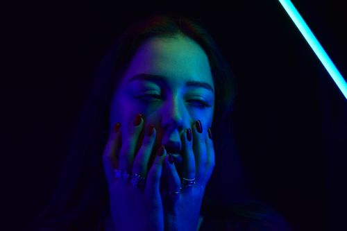 Free Close-up portrait of a woman with closed eyes under blue and green neon light. Stock Photo