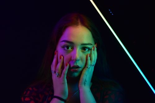 Free Vibrant portrait of a woman with rainbow lighting, showcasing jewelry. Stock Photo