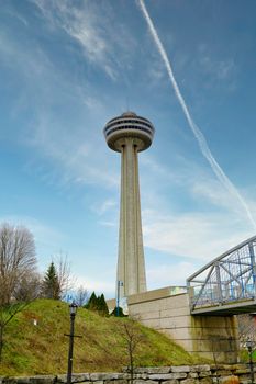 Stunning view of the Skylon Tower with a vivid blue sky and contrail overhead in Niagara Falls.