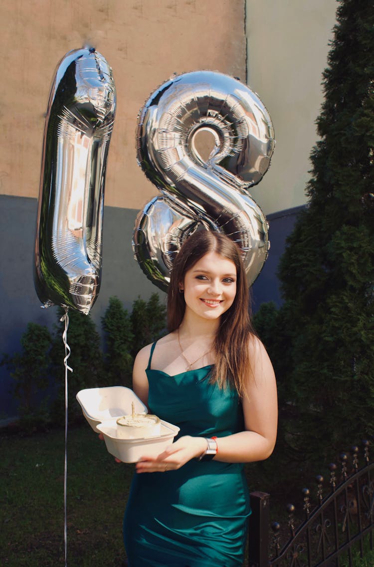 Smiling Woman Holding Birthday Cake Against Balloons