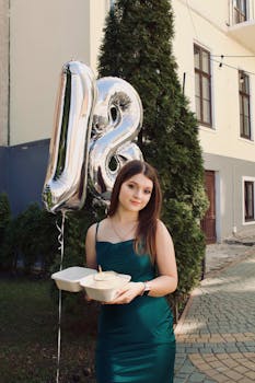 Young woman celebrating her 18th birthday outdoors holding cake and balloons.