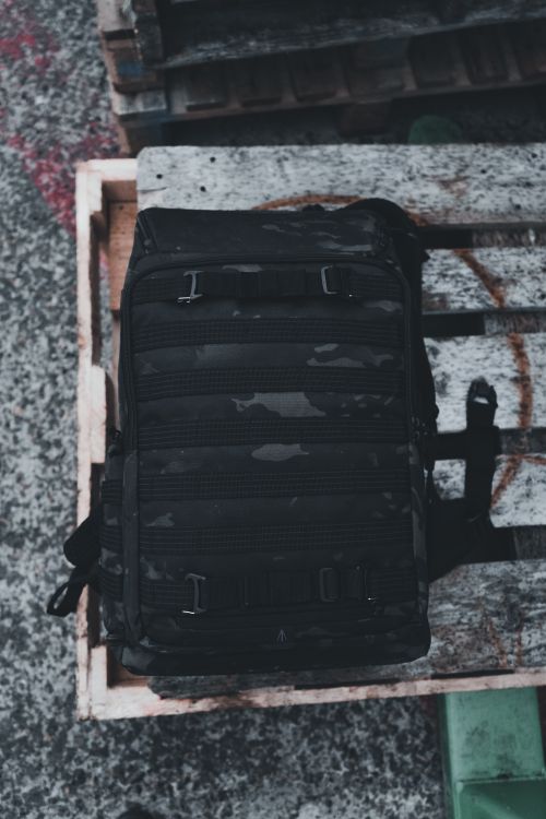 Free Camouflage backpack sits on a rustic wooden pallet, creating a travel-ready vibe. Stock Photo
