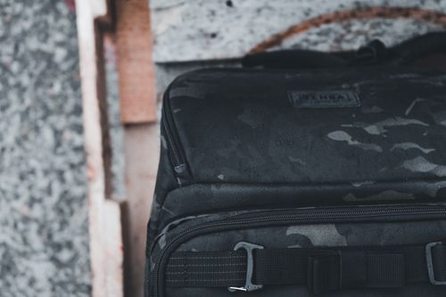 Free Camouflage backpack with visible logo in a rustic setting. Perfect for military or outdoor themes. Stock Photo