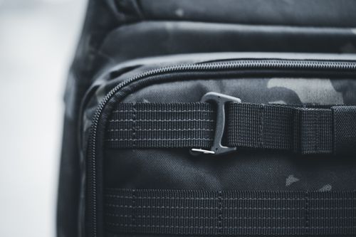 Free Detailed shot of a black tactical backpack highlighting the buckle and fabric texture, ideal for travel use. Stock Photo