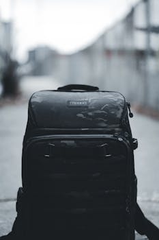 Close-up of a black backpack on urban pavement, capturing a moody travel vibe.