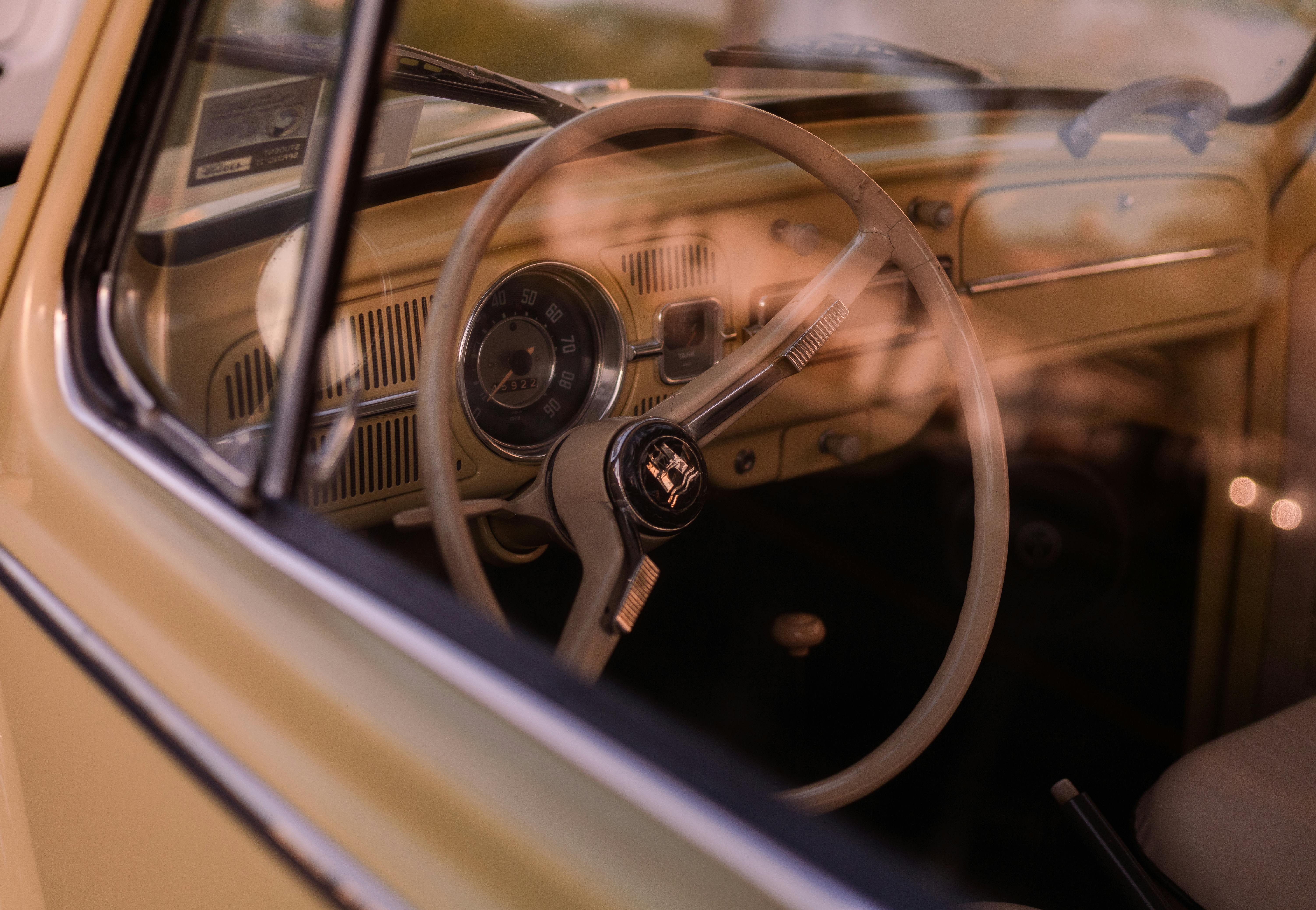 Interior view of a vintage Volkswagen Beetle car steering wheel and dashboard at sunset in Huntington Beach.