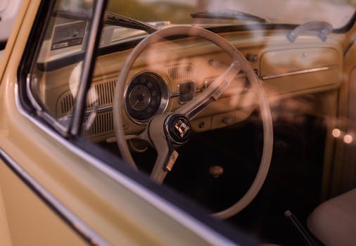 Interior view of a vintage Volkswagen Beetle car steering wheel and dashboard at sunset in Huntington Beach.