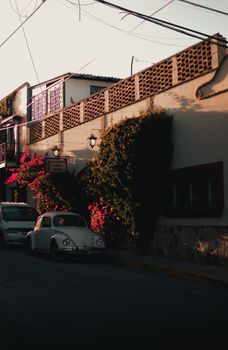 A picturesque urban alleyway with vintage cars at sunset, capturing nostalgic charm and shadow play.