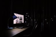 光线昏暗的家庭办公桌，通过发光的电脑显示器和装饰灯，营造出舒适的氛围