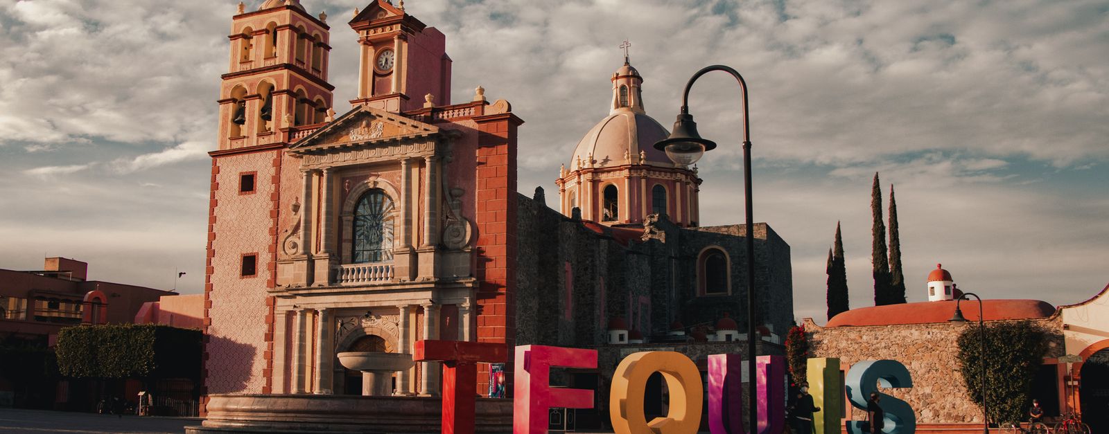 Charming town square in Tequisquiapan, Mexico, featuring a historic cathedral under a cloudy sky.