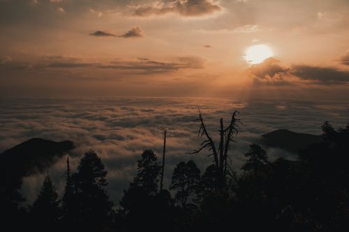 Free Breathtaking view of a sunset casting golden hues over a cloud-covered mountain range in Querétaro, Mexico. Stock Photo