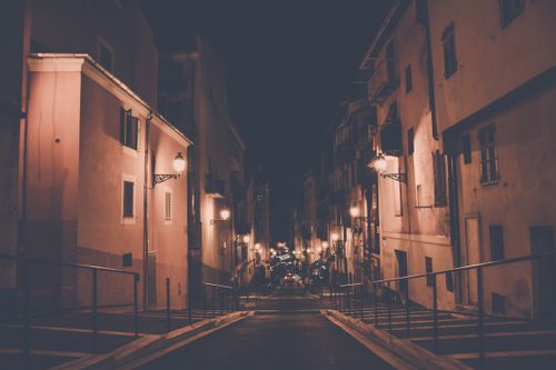 Free Cozy urban street view illuminated by warm streetlights creating a serene night atmosphere. Stock Photo