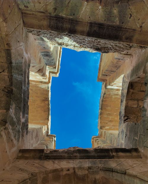 Free Upward view through ancient stone ruins with clear blue sky visible, showcasing historical architecture. Stock Photo