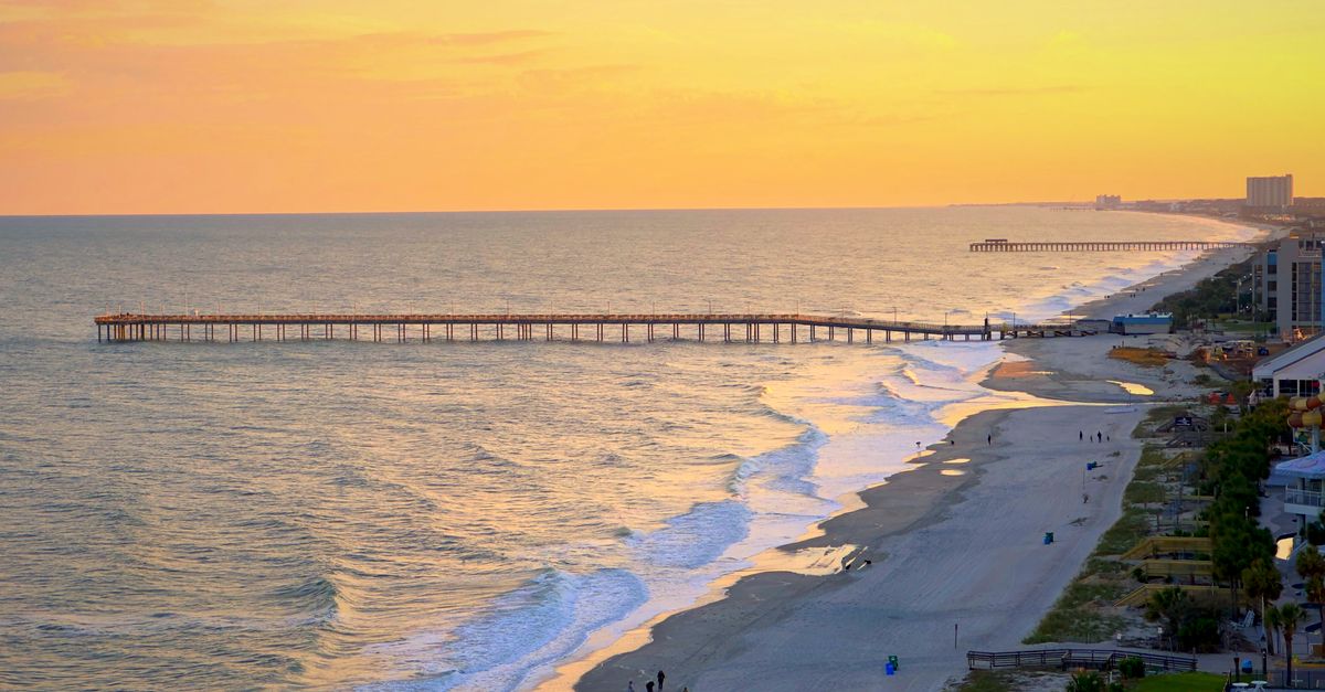 Stunning aerial view of Myrtle Beach, SC at sunset with pier extending into the ocean.