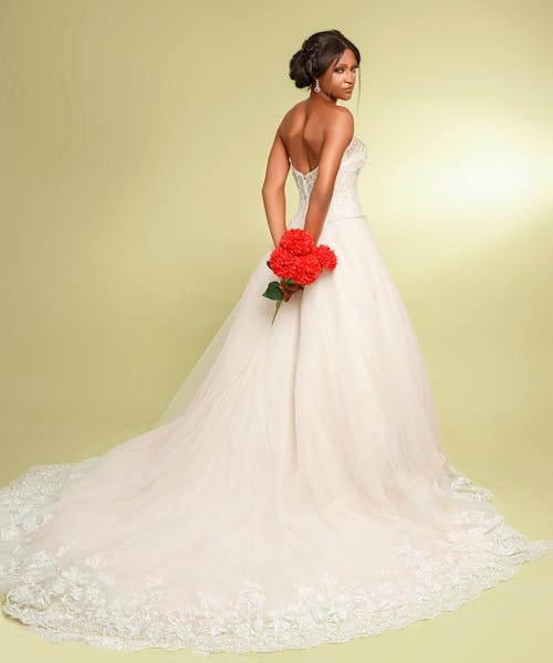 Woman in a Wedding Dress with a Bouquet of Red Flowers