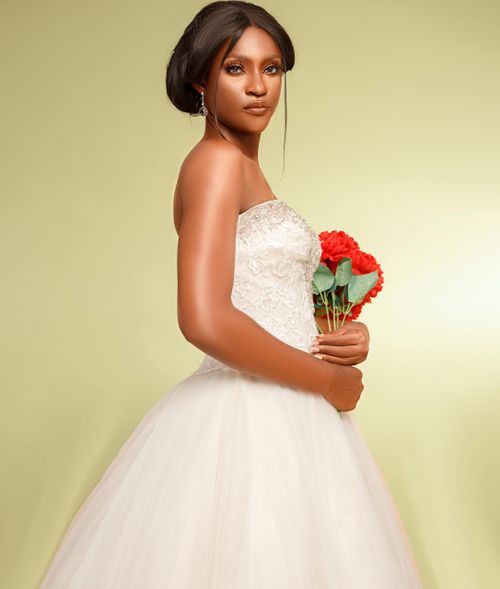 Free Beautiful bride in a wedding dress holding a bouquet of red flowers against a yellow backdrop. Stock Photo