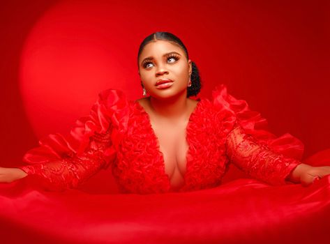 Elegant portrait of a woman posing in a bold red satin dress with dramatic lighting.