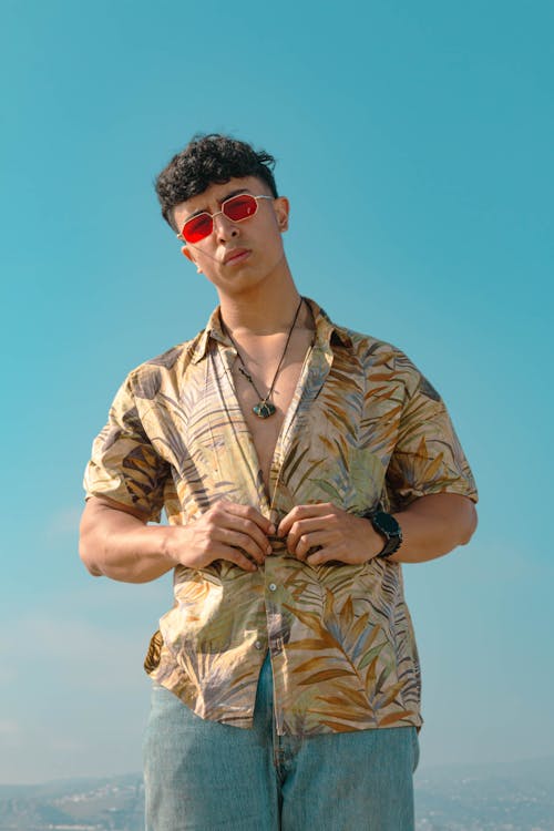 Young Man in a Shirt Standing on the Background of a Blue Sky 