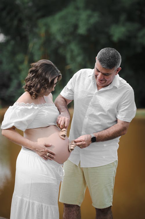 https://images.pexels.com/photos/16362350/pexels-photo-16362350/free-photo-of-man-holding-baby-shoes-on-pregnant-woman.jpeg?auto=compress&cs=tinysrgb&dpr=1&w=500
