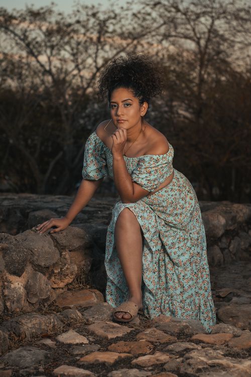 Free Woman in floral dress posing outdoors at sunset, exuding elegance and style. Stock Photo