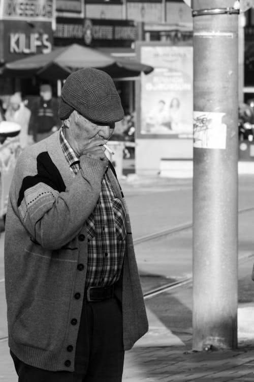 Free Candid Picture of an Elderly Man Smoking a Cigarette on the Sidewalk in City  Stock Photo