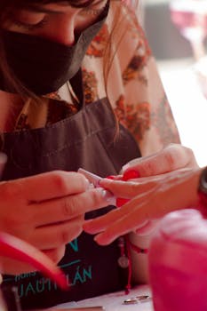Beautician carefully applying nail extensions in a salon.