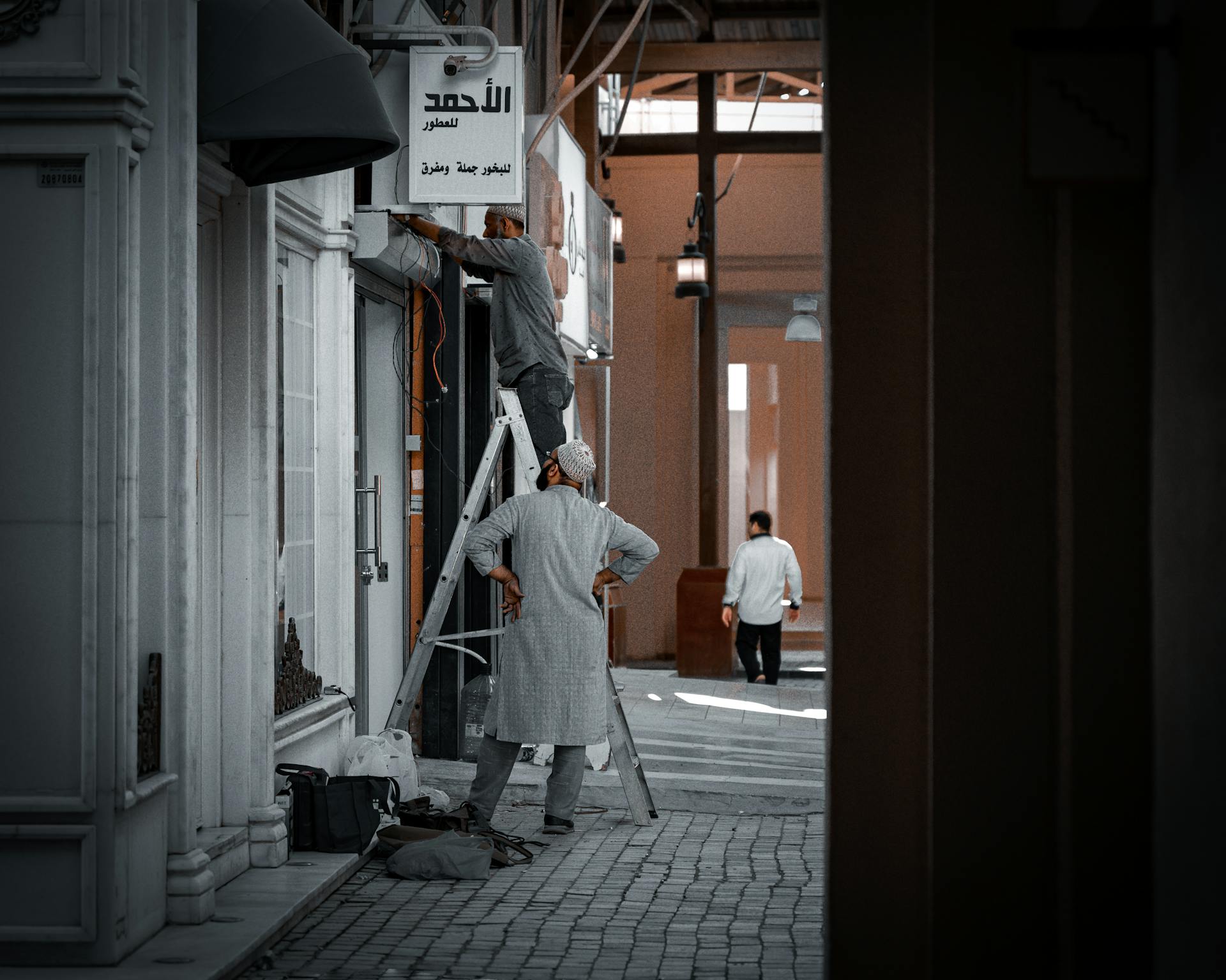 Men working on a ladder in an urban street of Kuwait City.