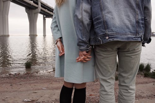 Free Man And Woman Holding Hands Near Body Of Water Stock Photo