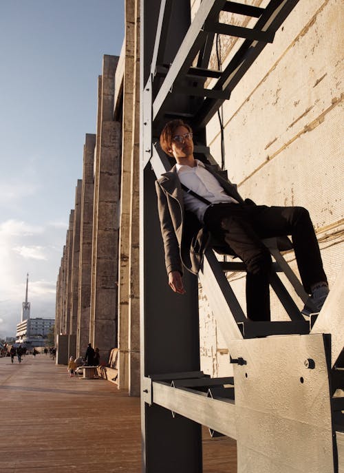 Foto De Un Hombre Sentado En La Escalera De Metal Gris