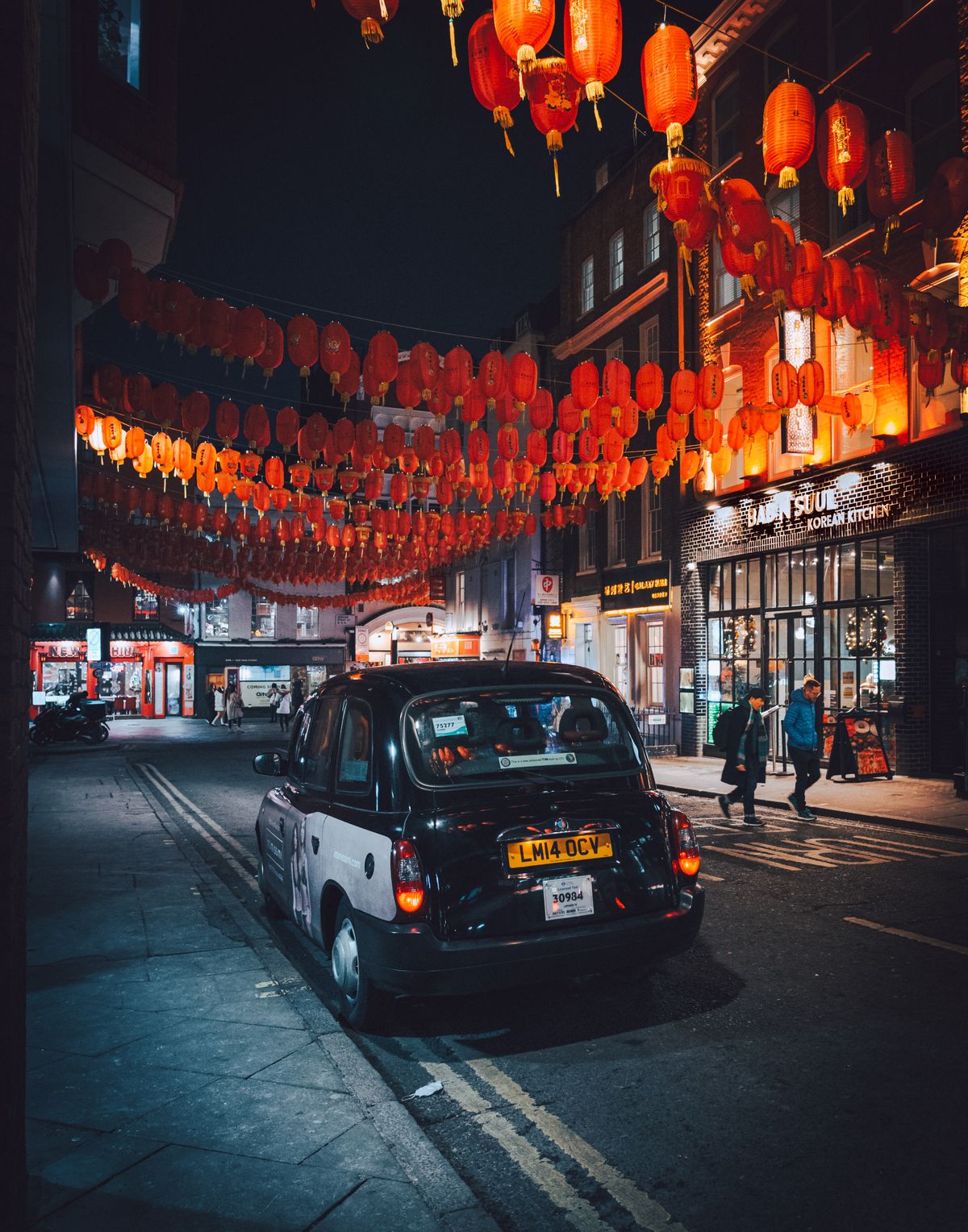 A cab drives through a UK Chinatown gate at night