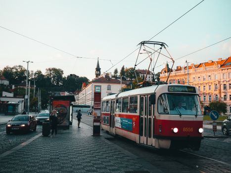 Charming vintage tram captured on the cobblestone streets of Prague at sunset, showcasing urban life and historic architecture.