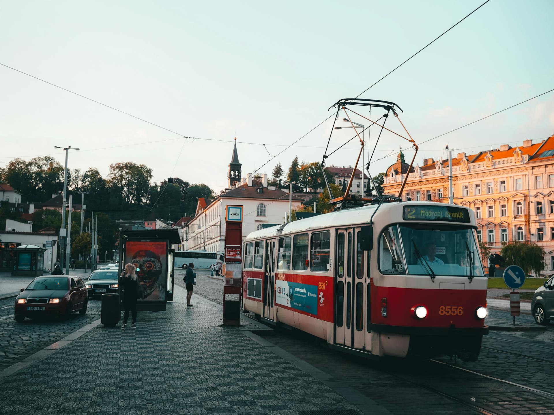 Charming vintage tram captured on the cobblestone streets of Prague at sunset, showcasing urban life and historic architecture.