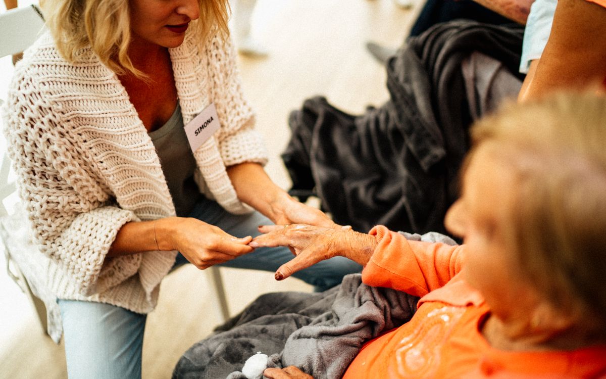 A caregiver assists a senior woman sitting comfortably indoors, emphasizing empathy and support.