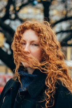 Captivating portrait of a redhead woman with curly hair outdoors in Kyiv.