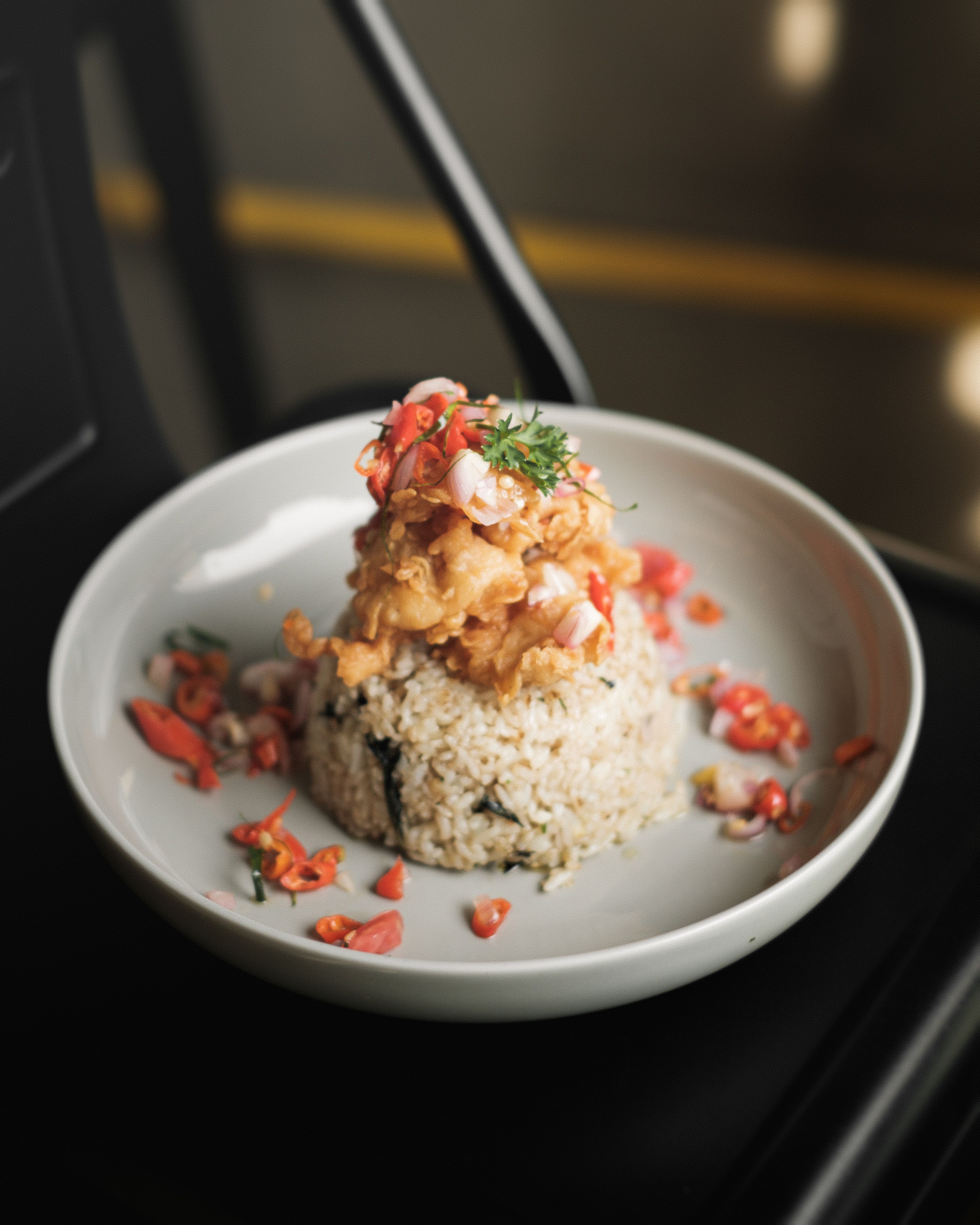A savory rice dish topped with a flavorful mix of proteins and vegetables, styled on a white plate.