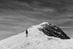 Silhouette of a person hiking towards a snowy mountain peak on a winter day.