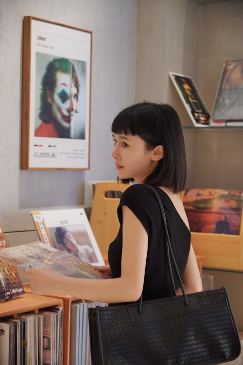 Young Woman with Vinyl Record in Hand in Shop