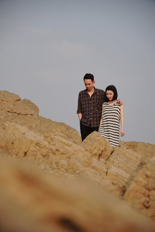 Couple Walking on Rocks against Sky Background