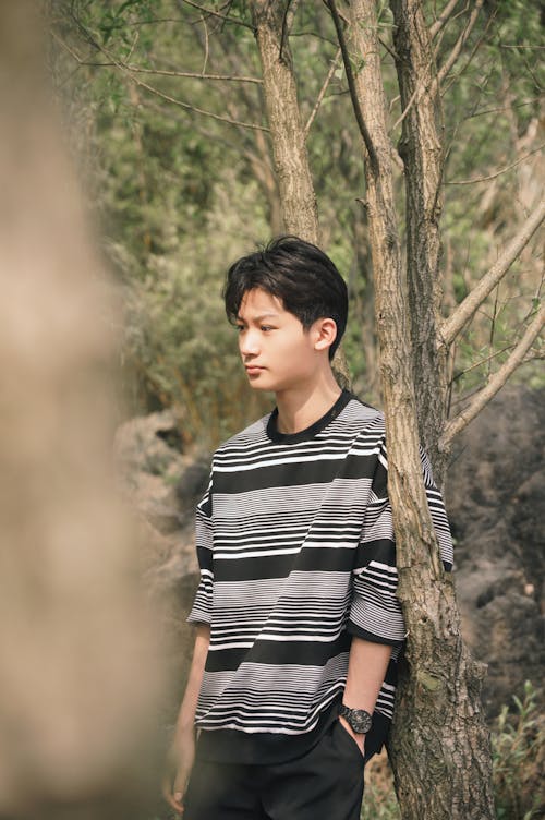 Young Man Posing near Tree in Forest