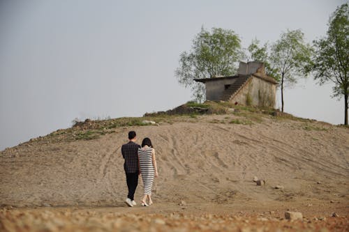 Young Couple Walking Towards the Old Demolished House