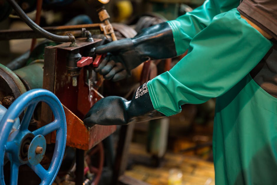 Industrial worker in protective gear handling a valve in a factory setting, ensuring safety and precision.