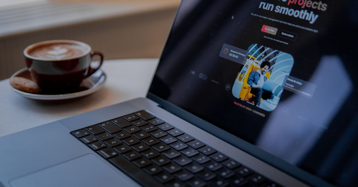 Portátil mostrando una aplicación de gestión de proyectos sobre una mesa con una taza de café
