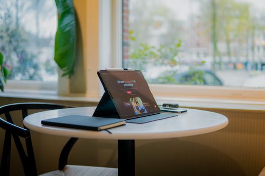 Tablet with notebook on a table near a window in an Amsterdam cafe, creating a cozy work atmosphere.