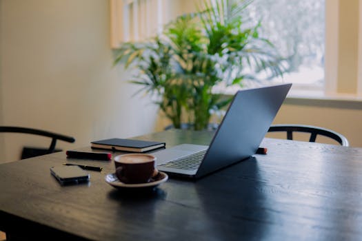 A warm, inviting workspace in Amsterdam featuring a laptop, coffee, and potted plant.