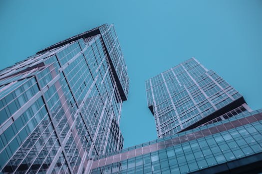 低角度视角下的未来派摩天大楼，反光玻璃外墙映衬着清澈的蓝天
