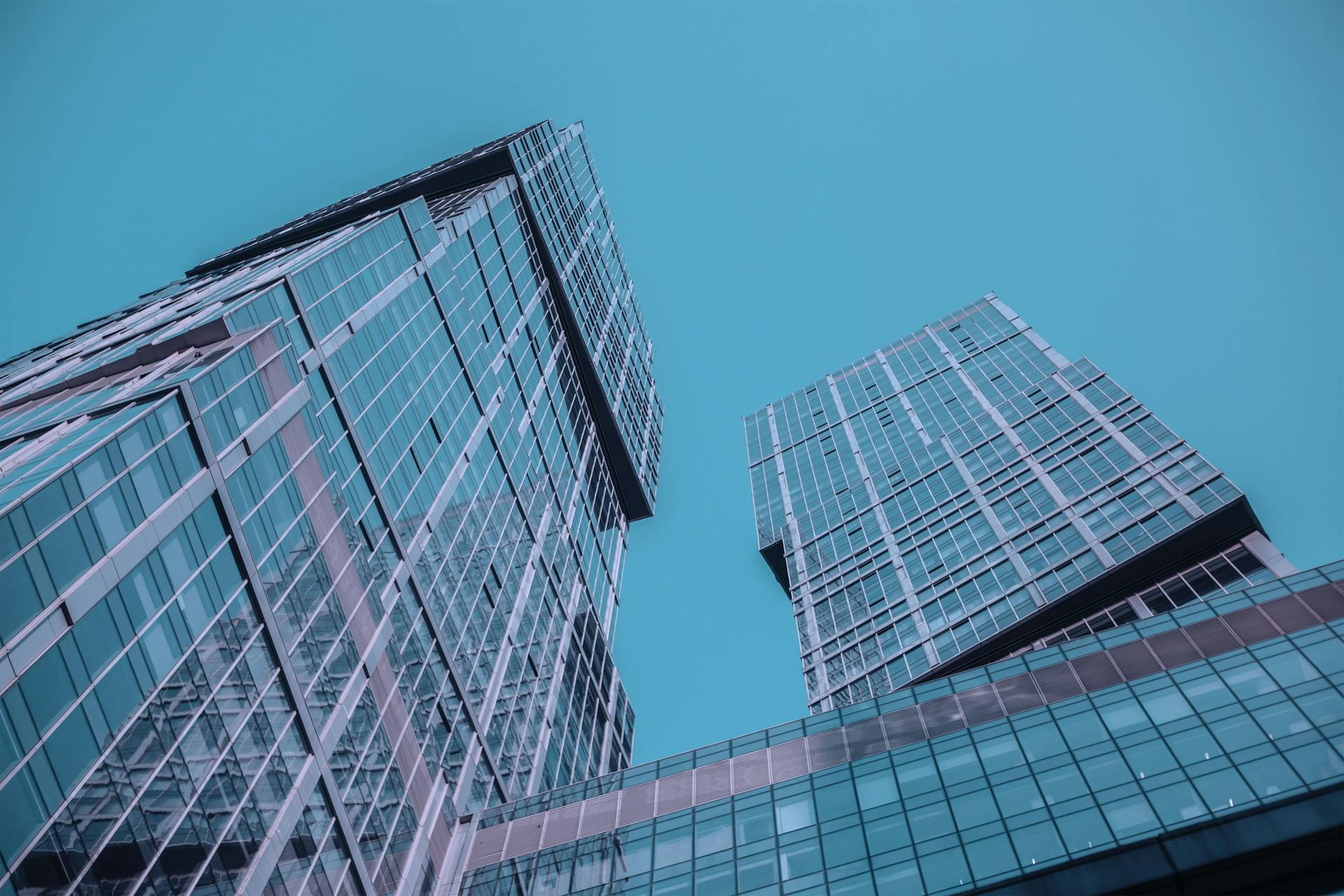 Low angle view of futuristic skyscrapers with reflective glass exteriors against a clear blue sky.