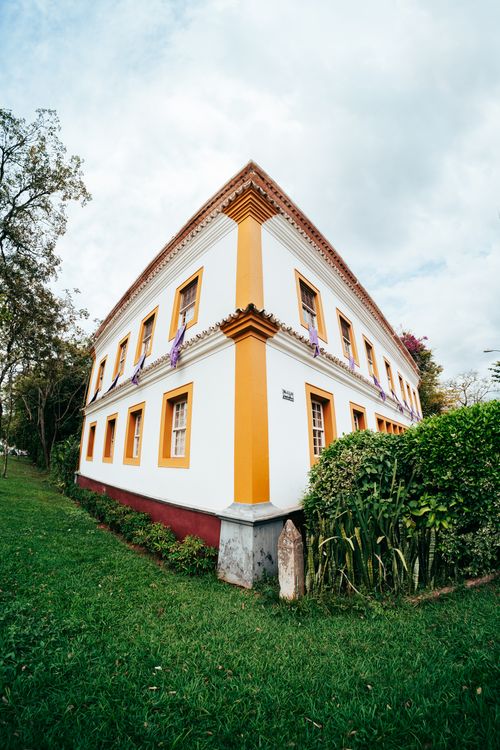 Free Colonial architecture building in lush garden, Tiradentes, Brazil. Vibrant yellow and white facade. Stock Photo
