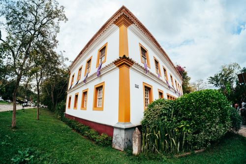Free Explore the vibrant colonial architecture in Tiradentes, MG. A beautiful corner building amidst lush greenery. Stock Photo