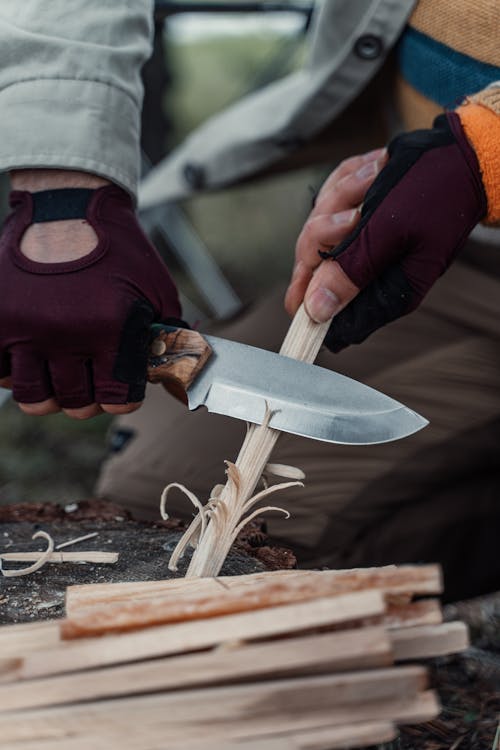 Man Hands Holding Knife and Cutting Wooden Sticks