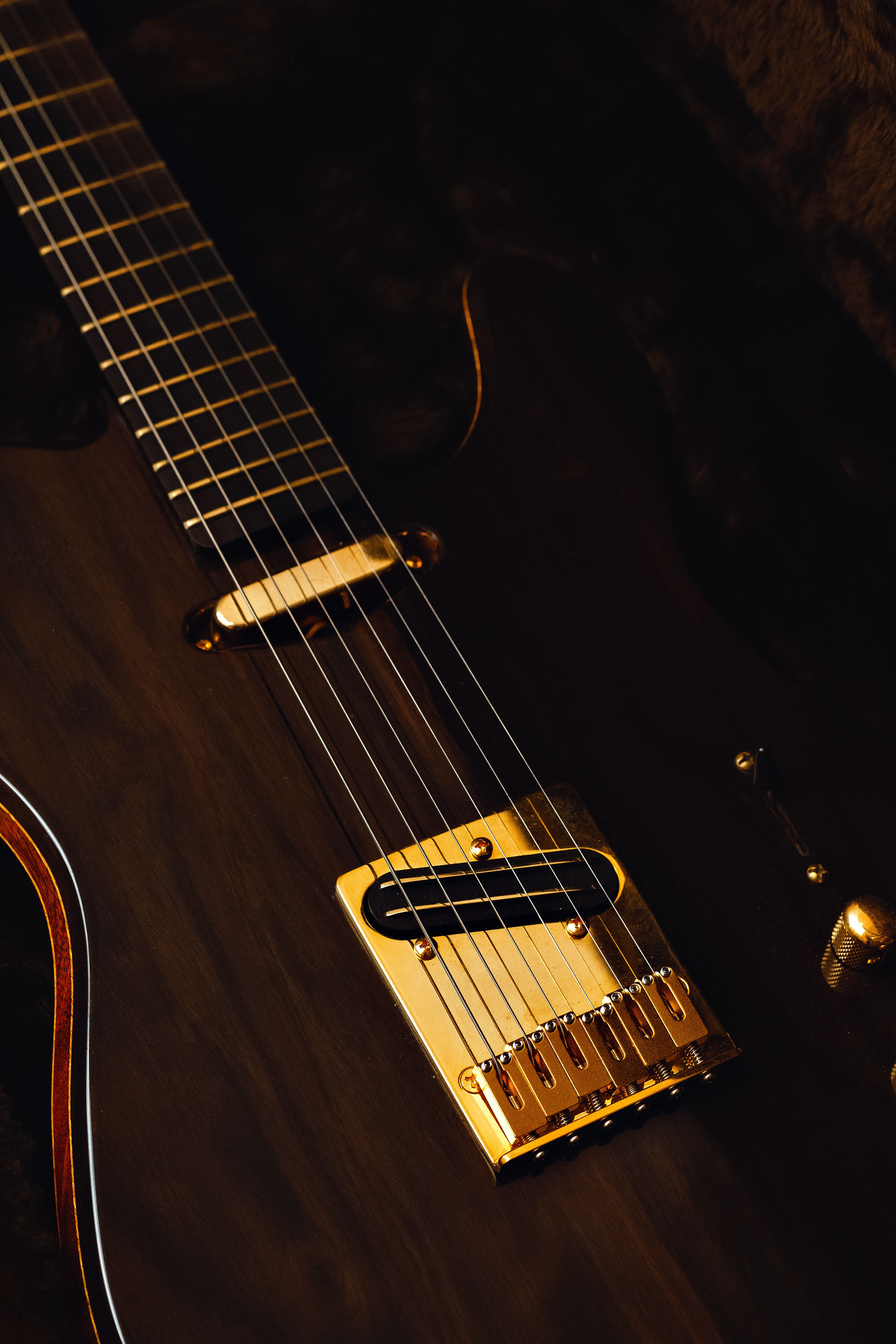 A detailed close-up of a dark electric guitar showcasing its strings and frets.